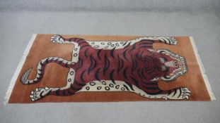 A fine handmade Tibetan rug with a tiger set on a terracotta field. L.180 W.86 cm