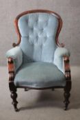 A Victorian mahogany framed armchair in deep buttoned upholstery raised on baluster turned supports.