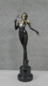 A patinated brass erotic figure of a dominatrix with whip on a black pedestal base. H.49 Diam.12cm