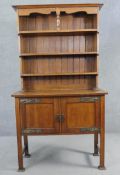 A late 19th century oak Arts and Crafts dresser with open plate rack above panel doors with embossed