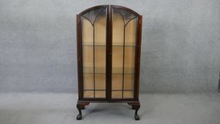 An early 20th century mahogany domed top display cabinet with astragal glazed doors enclosing