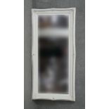 A contemporary bevelled wall mirror in carved and painted frame. H.180 W.84cm