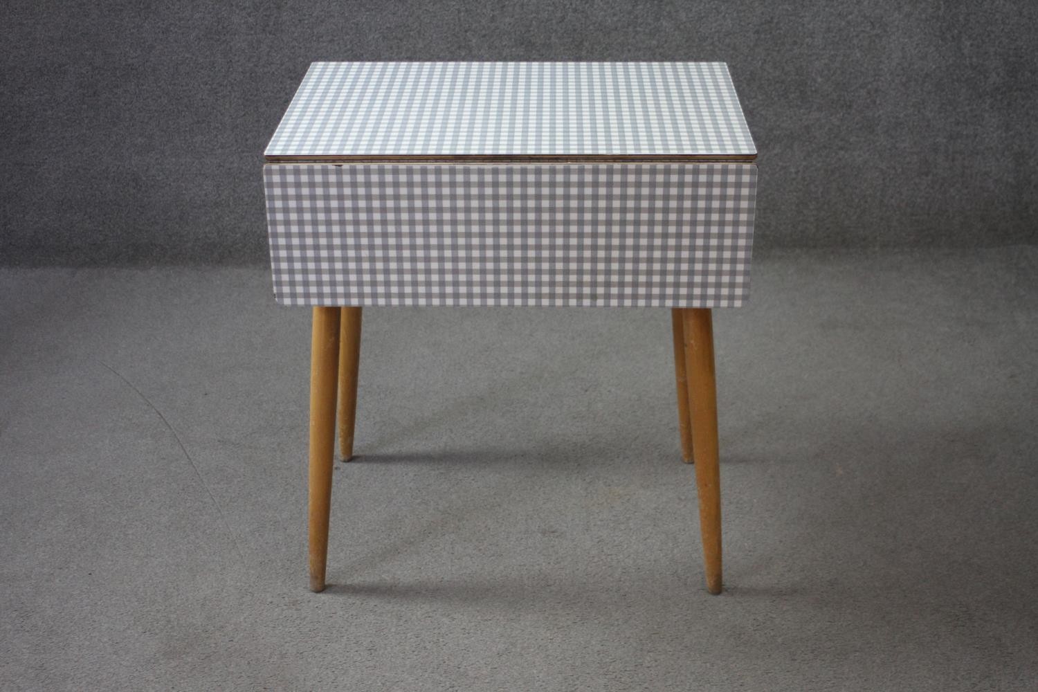 A mid century vintage drop flap kitchen table with gingham check laminated top. H.74 W.89 D.68 cm.