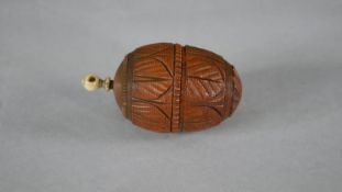 A 19th century carved coquilla nut sewing case in the form of an acorn with foliate design and