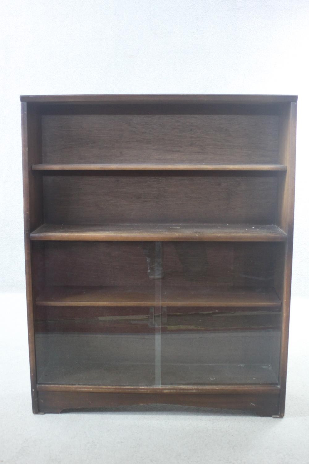 A vintage teak bookcase with open shelves above sliding plate glass doors. H.113 W.91 D.25 cm.