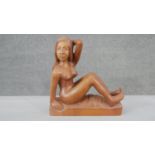 A carved hardwood figure of a nude seated woman on rectangular base. H.28 W.26 D.9cm