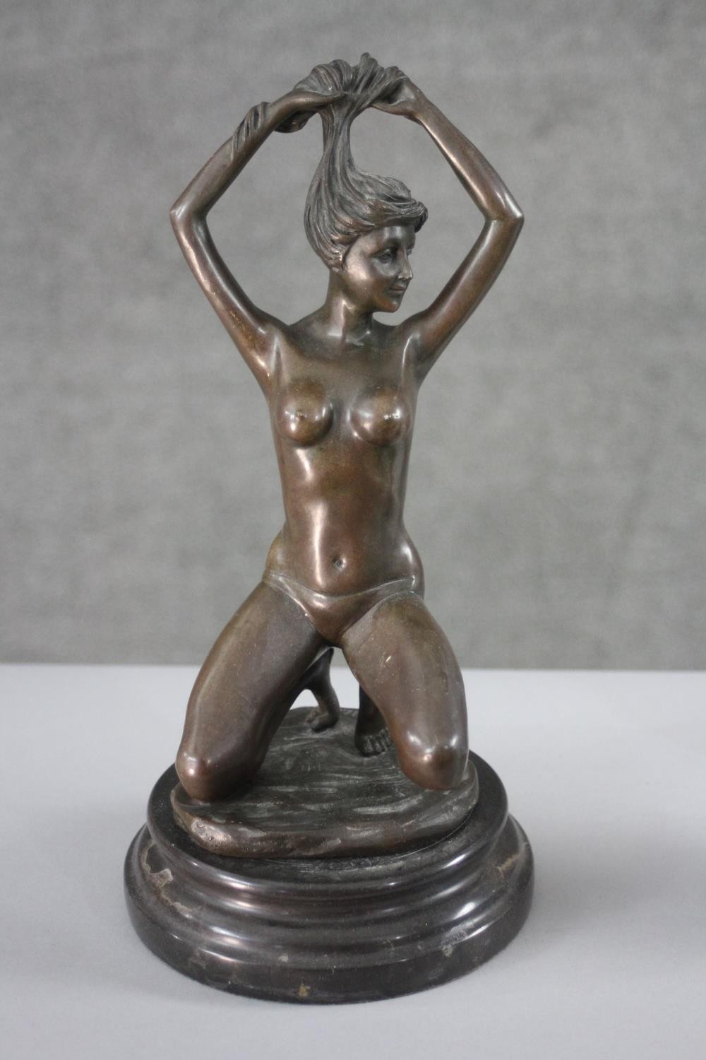 An erotic spelter figure of a kneeling nude woman holding up her hair. H.30 W.16 cm.