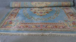 A large Chinese woollen carpet with central floral medallions surrounded by garlands on a sky blue