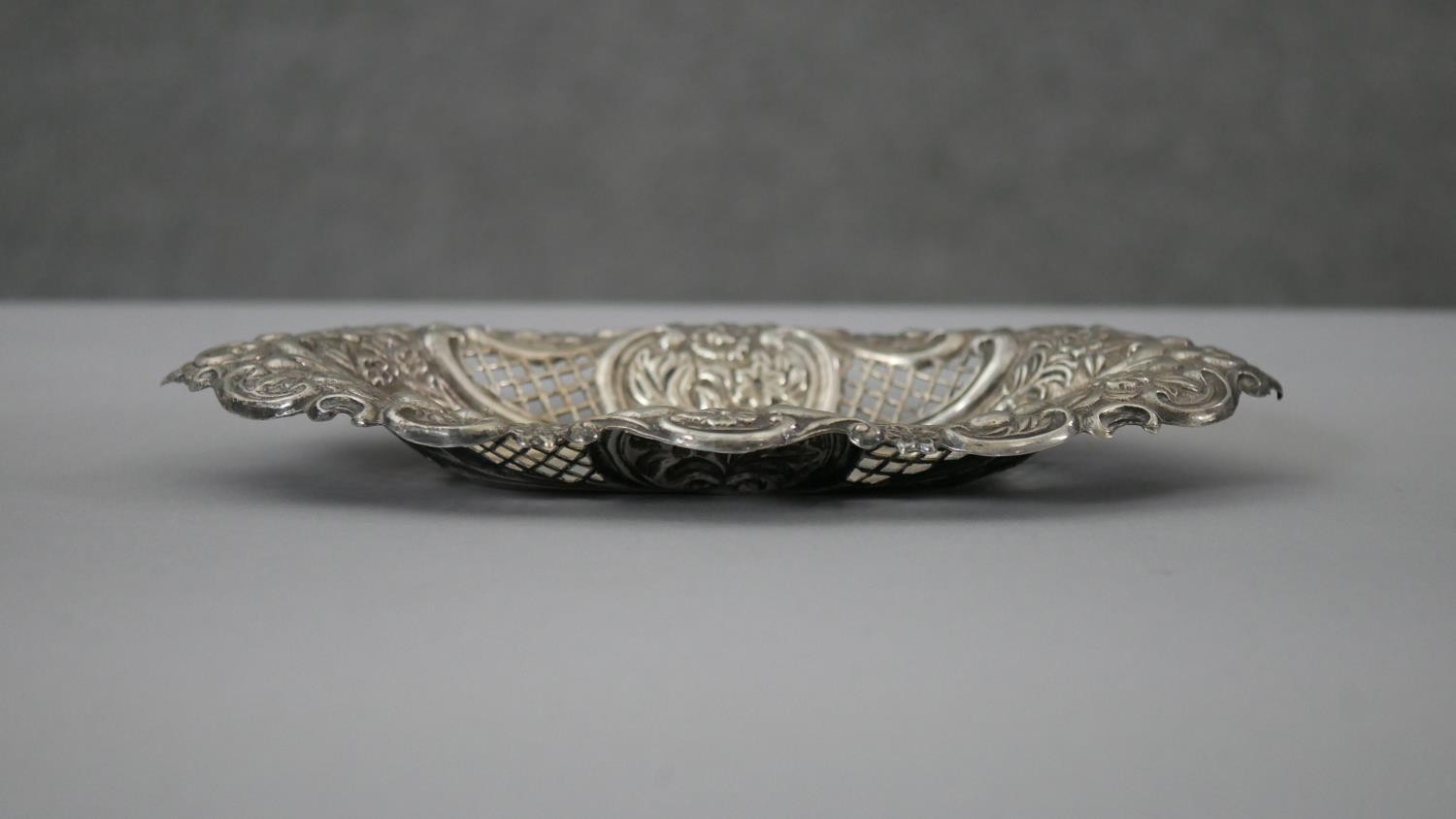 A Victorian pierced repousse design silver pin dish with floral and scrolling motifs and pierced