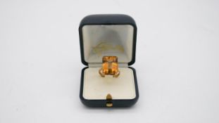 A 9 carat rose gold andcitrine dress ring. Set to centre with an emerald cut citrine with an