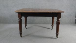 An early 19th century mahogany extending dining table with extra leaf on carved turned and