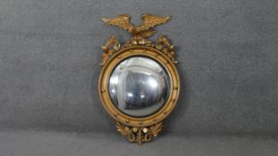 A Regency style giltwood convex mirror with carved ho ho bird cresting and foliate decoration. H.