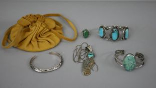 A collection of Native American turquoise jewellery with a yellow suede pouch. Including two
