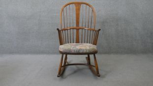 A vintage Ercol rocking chair with hooped spindle back and fitted cushion on elm seat with maker's