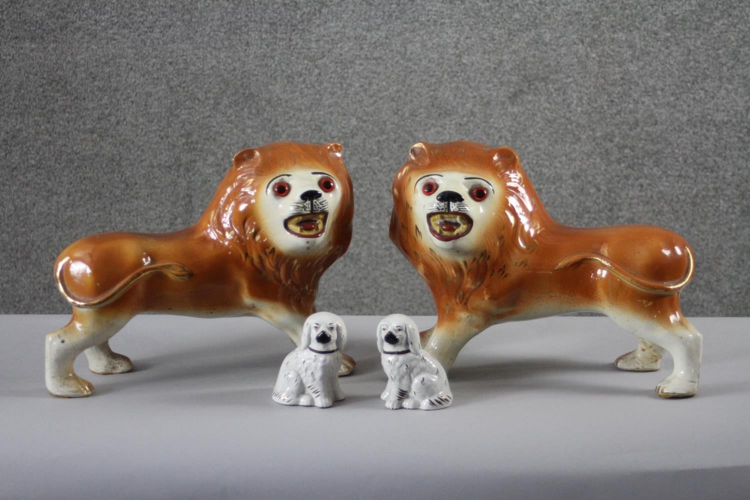 A pair of 19th century Staffordshire pottery lions with glass eyes along with a pair of