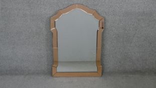 A mid century Venetian style wall mirror with shaped peach glass frame. H.79 W.54 cm