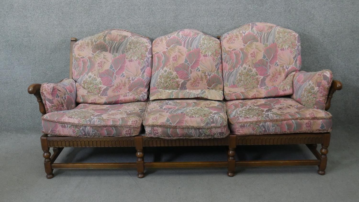 A vintage carved oak three seater sofa in the country antique style with fitted floral cushions. H.