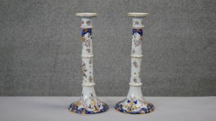 A pair of early 20th century French faience hand painted candlesticks. Signed and numbered to the