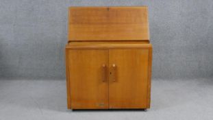 A mid century vintage light oak bureau with fitted interior above panel doors revealing drawers. H.