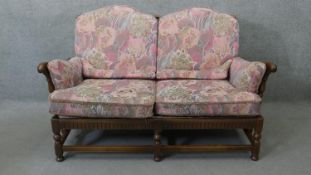 A vintage carved oak two seater sofa in the country antique style with fitted floral cushions. H.