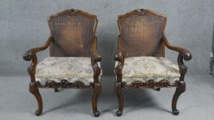 A pair of early 20th century carved walnut Continental style armchairs with caned backs above cut