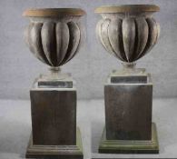 A pair of very large aged stone effect fibreglass gadrooned design garden urns on square stepped