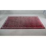 A Persian Meshed rug with repeating stylised flowerhead motifs across the field contained within