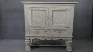 An early 20th century distressed painted 18th century style cabinet with all over carving on