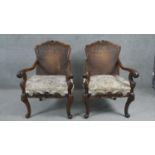 A pair of early 20th century carved walnut Continental style armchairs with caned backs above cut