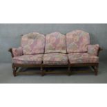 A vintage carved oak three seater sofa in the country antique style with fitted floral cushions. H.