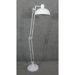 A large white enamel retro styled adjustable angle poise design floor lamp on circular base and with