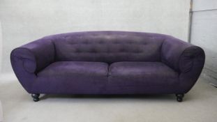 A contemporary scroll arm sofa in buttoned velour upholstery on shaped bun supports. H.86 W.232 D.93