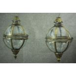 A pair of Victorian style globe shaped glass and brass wall mounted lanterns with scrolling wall