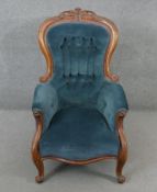 A Victorian carved walnut framed armchair in deep buttoned velour upholstery on cabriole supports.