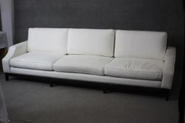 A large contemporary three seater sofa in piped calico upholstery on shaped ebonised supports. H.