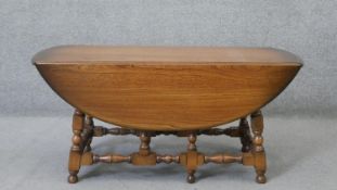 A vintage elm Ercol drop flap low table on turned tapering supports with maker's label to the