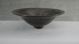 A large footed art pottery bowl with brown and black glaze with flared rim. (Damaged as seen in
