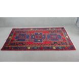 A Persian Hamadan rug with repeating central hooked medallions on a burgundy field within multiple