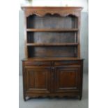 An 18th century French Provincial chestnut dresser with open plate rack above cupboards and