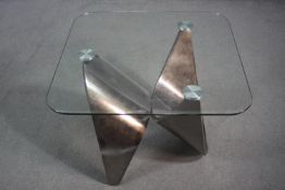 A contemporary occasional table with plate glass top on shaped brushed chromium base. H.55 W.71 D.71