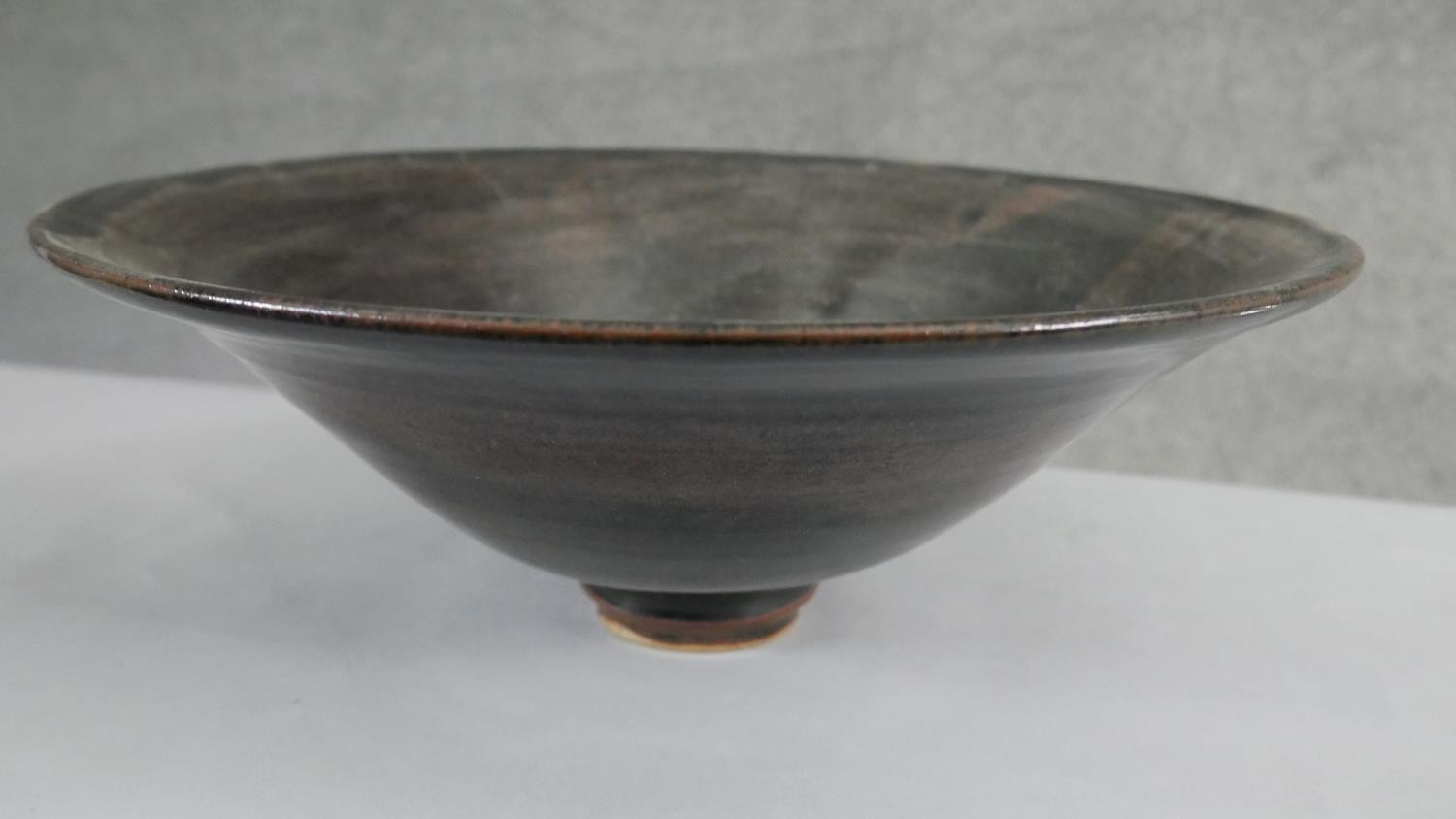 A large footed art pottery bowl with brown and black glaze with flared rim. (Damaged as seen in - Image 3 of 6