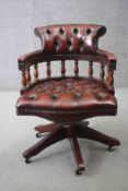 A mahogany framed captain's desk chair in deep buttoned leather upholstery with tilt and swivel