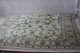 A Persian Keshan carpet with all over trailing foliate design on a biscuit ground within multiple