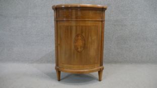 A Continental mahogany crossbanded bow fronted corner cabinet with central Classical urn inlaid