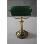 An early 20th century brass bankers desk lamp with green glass adjustable shade and on stepped