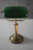 An early 20th century brass bankers desk lamp with green glass adjustable shade and on stepped