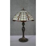 A vintage Tiffany style leaded stained glass table lamp with bronze effect foliate design base. H.60