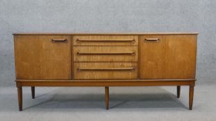 A mid century vintage teak sideboard fitted with three central drawers flanked by cupboards raised