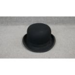 A Harrods of London small sized black bowler hat with silk and leather lining and gilded makers