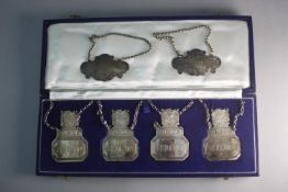 A collection of silver drinks labels. Including a blue leather cased set of engraved armorial